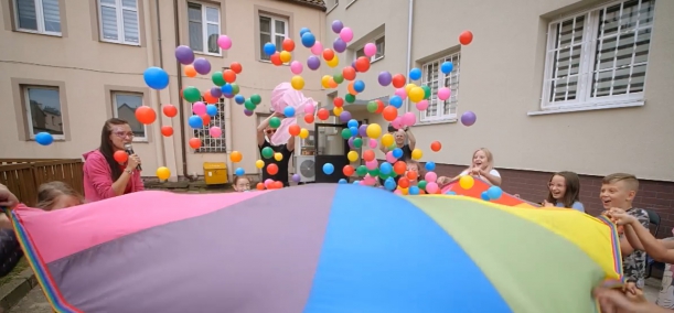 dzieci bawiące się kolorową chustą i piłeczkami 