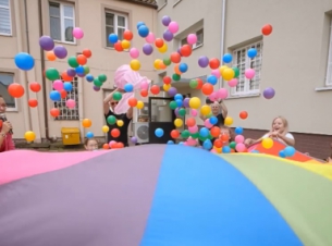 dzieci bawiące się kolorową chustą i piłeczkami 